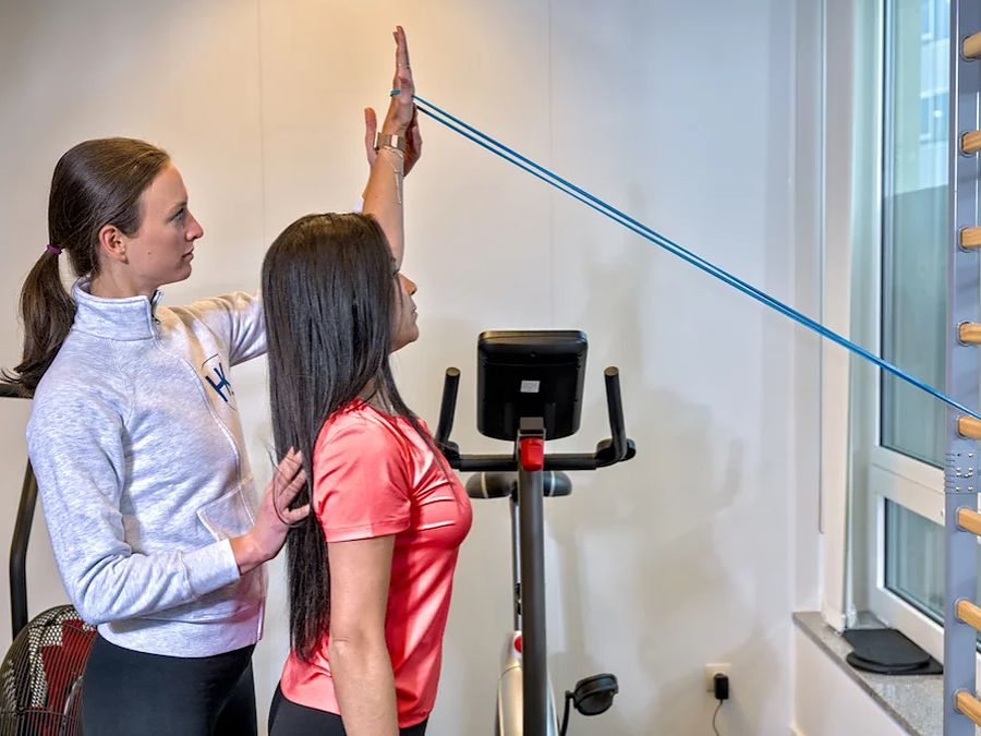 Une coach du HK Health Center guide une adhérente sur un exercice d’épaules